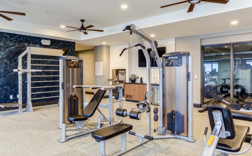 Spacious and well lit fitness center with free weights and cardio equipment.